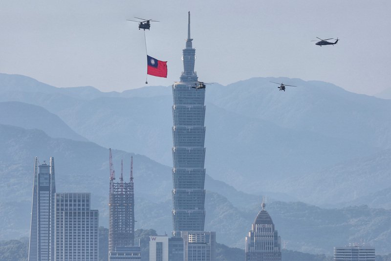 国軍部隊が29日午前5時50分から7時40分まで、総統府前広場の上空で10月10日の建国記念日、双十国慶節に行われる祝賀式典における空中のパフォーマンスの予行演習をパワー全開で行った。写真は、大きな国旗を掲げて台北市の上空を通過する、大型輸送ヘリコプター・CH-47と多目的軍用ヘリコプタ・UH-60M（ブラックホーク）。（写真：CNA）